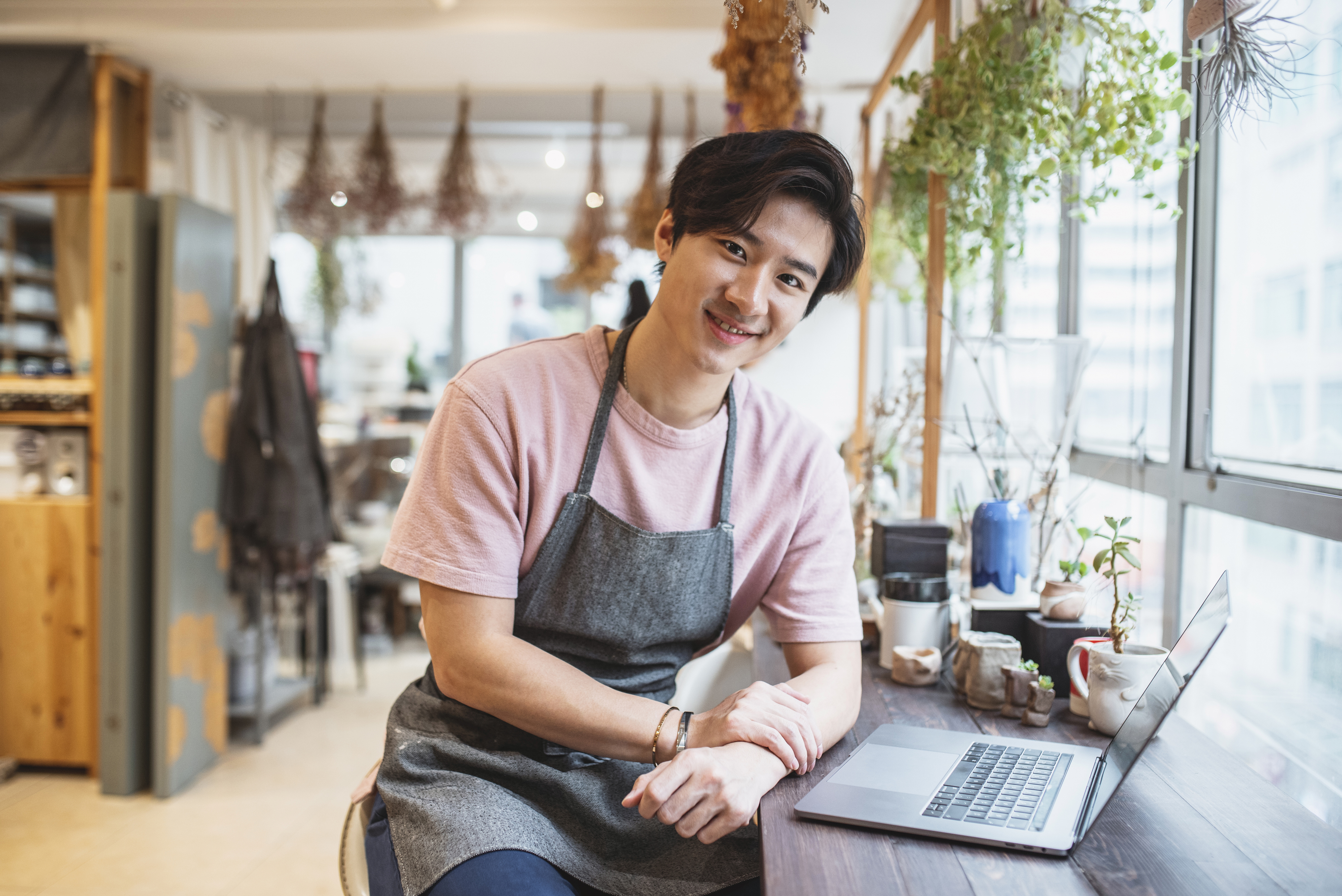 Young Chinese man using laptop and working in a pottery shop
